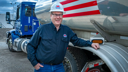 A smiling MPC driver posing to the side of his truck
