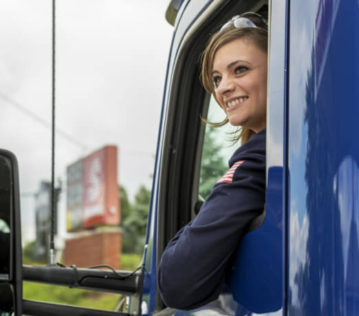 A female MPC truck driver looking out her window smiling.
