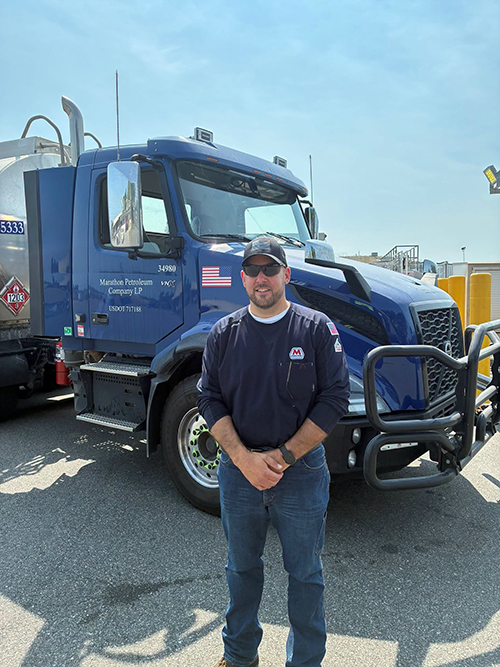 Man stands in front of a large truck.
