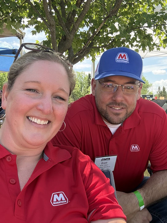 Two adults, a man and a woman, pose for a photo together outdoors.